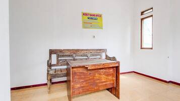 A room with a wooden bench, a tiled floor, a window, and a wall-mounted sign.