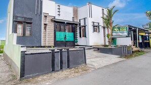 A modern building with a large green gate, a signboard, and a paved entrance area. - Cozy Double Escape W/ Free Wifi and Parking (Purwokerto)