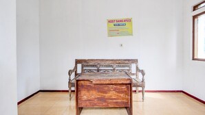A room with a wooden bench, a tiled floor, and a wall-mounted sign. - Cozy Double Escape W/ Free Wifi and Parking (Purwokerto)