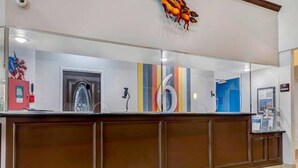 A reception desk with a large mirror, a coat rack, and a wall-mounted number sign.