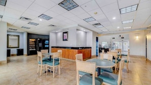 A spacious indoor area with a reception desk, several tables and chairs, and a tiled floor.