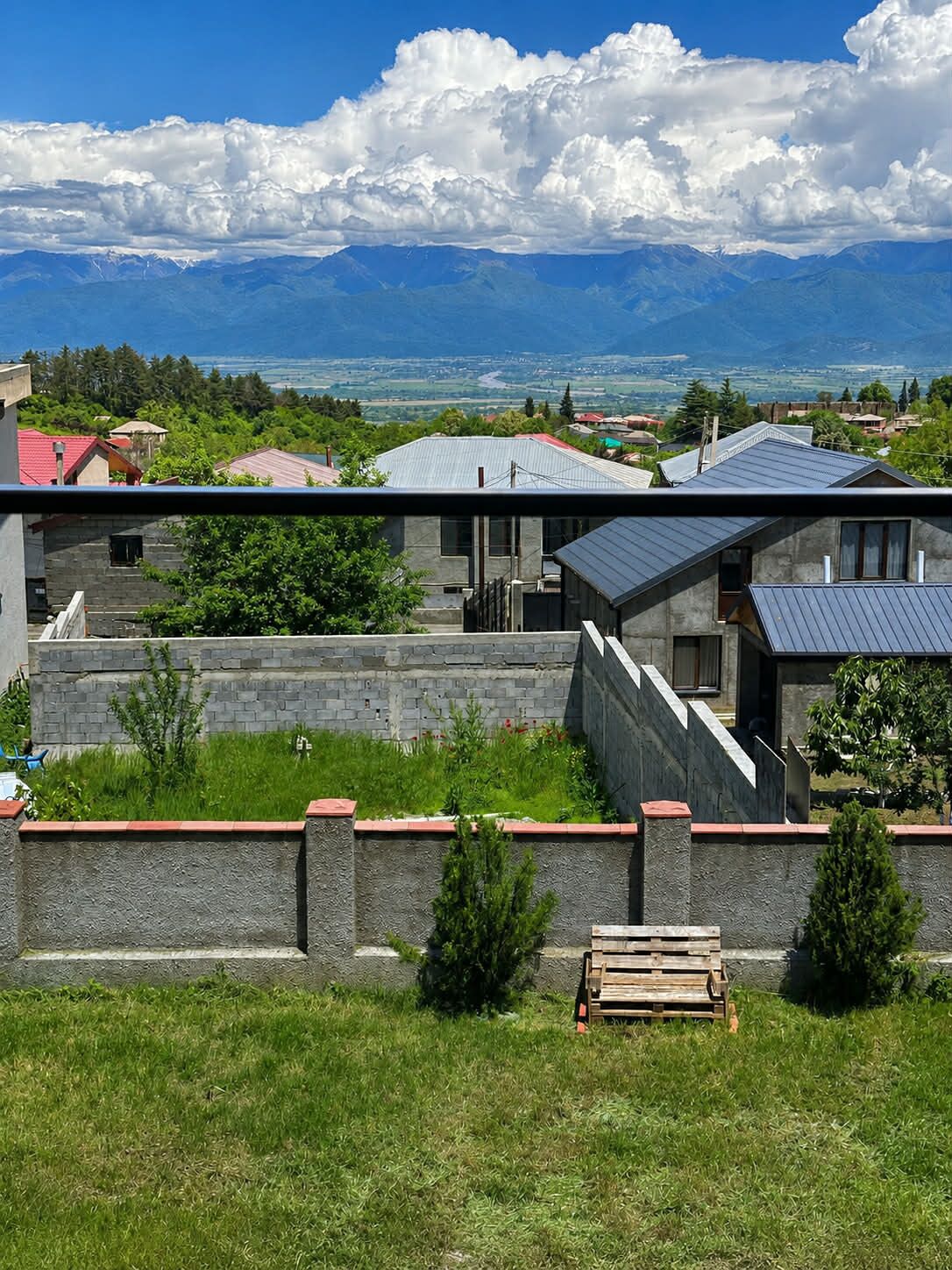 Ein modernes Haus mit einer Steinwand, einer Holzbank und Blick auf ferne Berge.