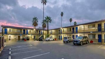 Un motel con varias habitaciones, un estacionamiento y palmeras.