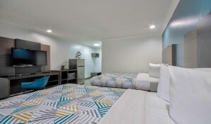 Une chambre d’hôtel avec un lit, un bureau avec une télévision, une chaise et un tapis à motifs.