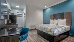 A modern hotel room with a bed, a desk, and a chair.