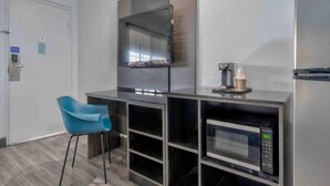A kitchenette with a microwave, coffee maker, and a flat-screen TV.