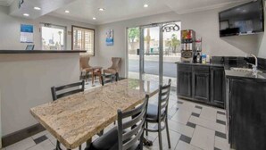 A hotel room with a dining area, a kitchenette, and a TV mounted on the wall.