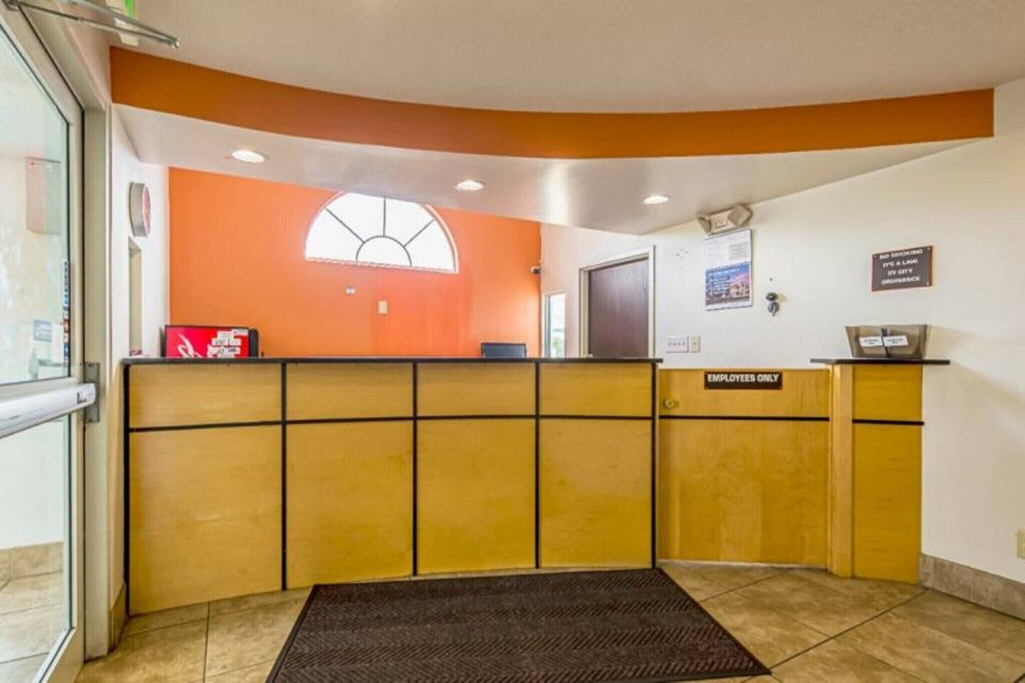 Un espace d’accueil avec un comptoir incurvé, un panneau indiquant « Réservé au personnel », une fenêtre donnant sur l ’extérieur et une horloge fixée au mur.