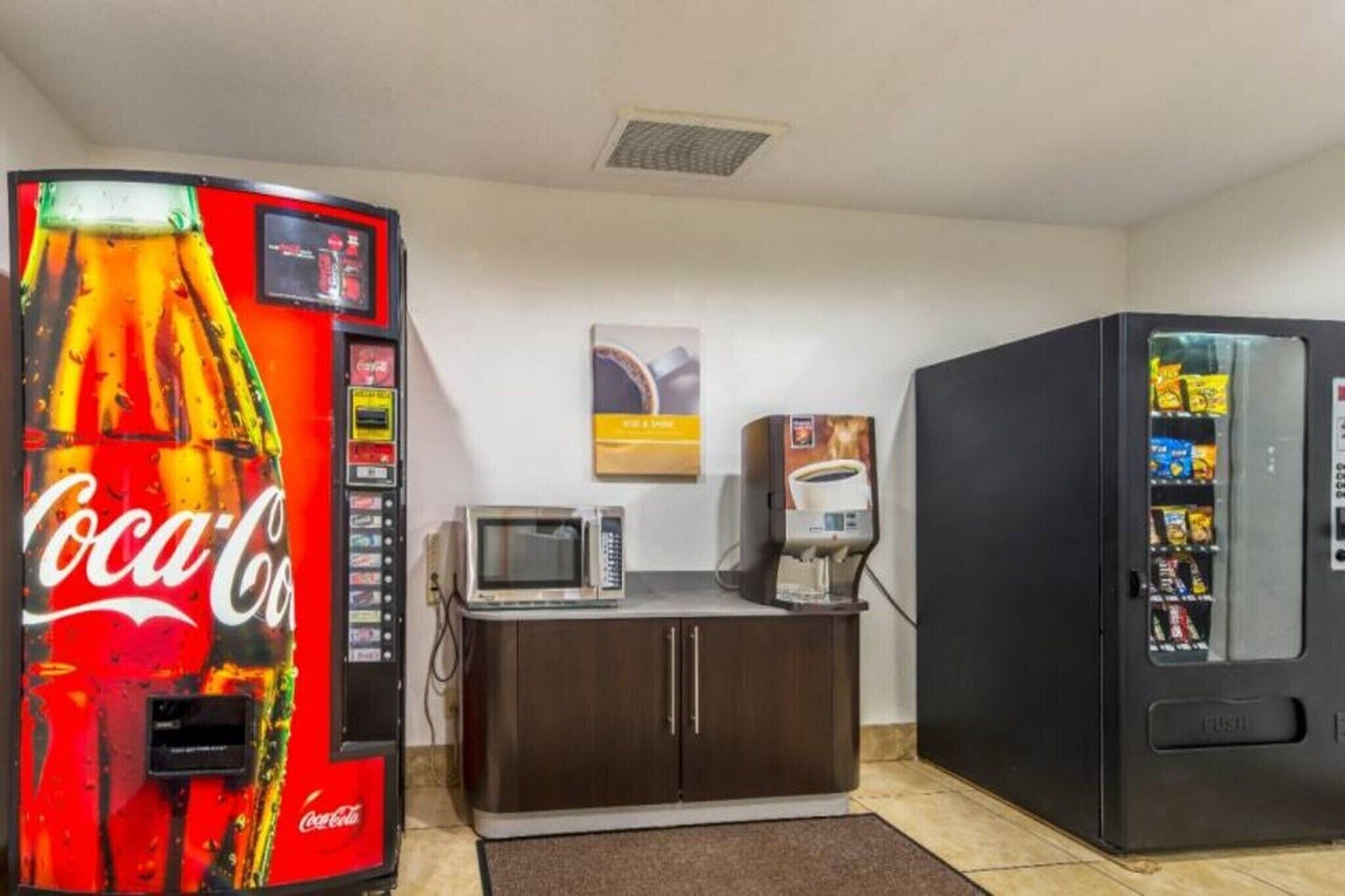 Une pièce équipée d’un distributeur automatique de Coca-Cola, d’un four à micro-ondes, d’une machine à café et d’un autre distributeur automatique de collations.