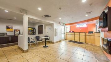 A reception area with a counter, chairs, a small table, and a microwave.