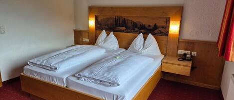 A double bed with a wooden headboard, two bedside tables, and a wall-mounted lamp.