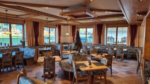 A restaurant with wooden furniture, large windows, and a Christmas tree. - Hotel Dahoam by Miha (Westendorf)