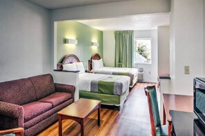 A room with two beds, a sofa, a small table, and a TV. - 2 Queen Beds|Suite,Smk,Sofa-Bed (Dallas)