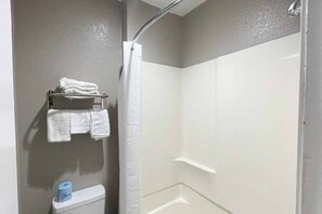 Un baño con ducha, inodoro y toallero con toallas dobladas.