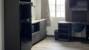 Eine kleine Küche mit Kühlschrank, Spüle und einem Fenster mit Vorhängen.