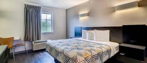 A modern hotel room with a large bed, a flat-screen TV, a desk, and a chair.
