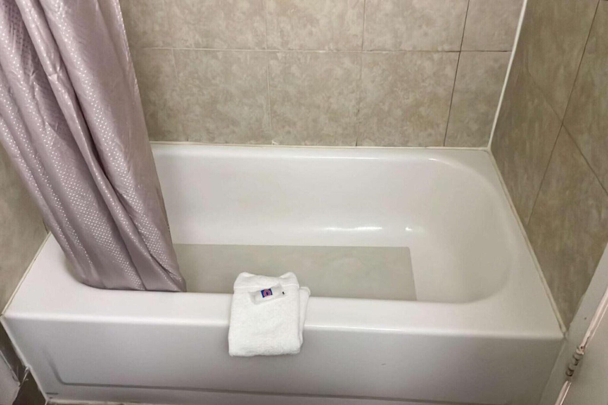 Ein Badezimmer mit einer Badewanne, einer Duschvorhang und einem Handtuch, das an der Wand hängt.