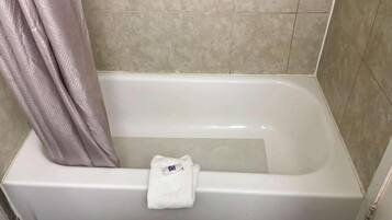Ein Badezimmer mit einer Badewanne, einer Duschvorhang und einem Handtuch, das an der Wand hängt.