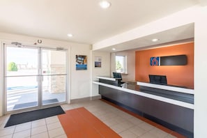 A reception area with a glass door entrance, a reception desk, and a wall-mounted sign.