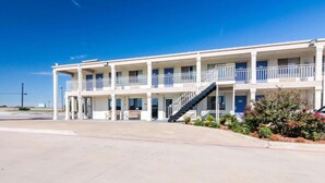 A multi-story hotel with balconies, a central staircase, and a parking lot. - 1 King Bed | Mobility Accessible Tub, Nsmk (Wichita Falls TX)