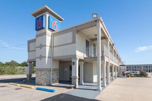 A motel with a prominent '6' sign, a covered entrance, and a parking lot.