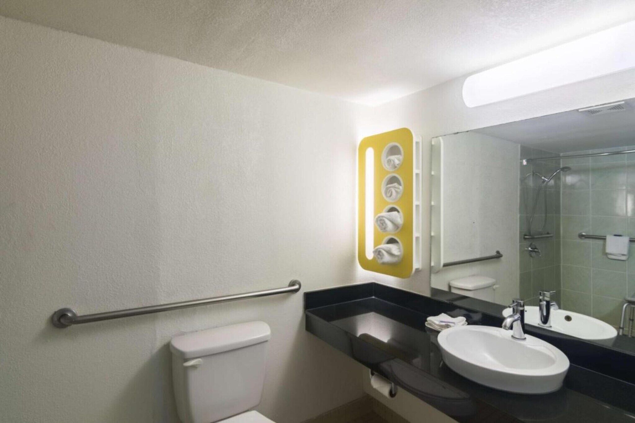 Ein Badezimmer mit Toilette, Waschbecken, Spiegel und Dusche.