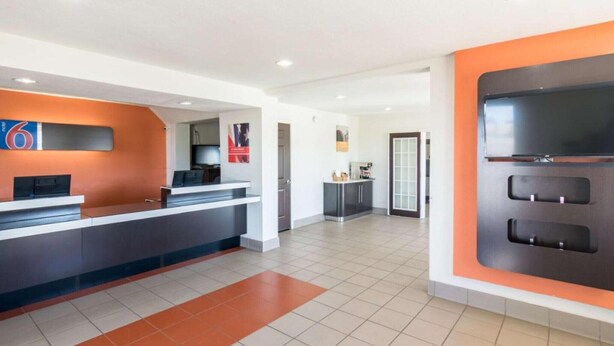 A hotel reception area with a counter, a digital display, and a large screen. - 2 Queen Beds | Mobility Accessible Tub Nsmk (Wichita Falls)