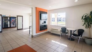 A modern indoor space with a vending machine, seating area, and a large window. - 2 Queen Beds | Mobility Accessible Tub Nsmk (Wichita Falls)