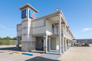 A motel with a prominent '6' sign, a covered entrance, and a parking lot.