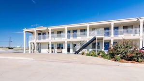 A multi-story hotel with balconies, a central staircase, and a parking lot. - 2 Queen Beds | Mobility Accessible Tub Nsmk (Wichita Falls)