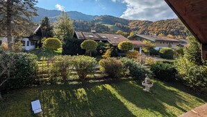 A view of a house with a garden, surrounded by trees and hills. - Apartment Gigi 100 m², 2-6 persons, living room, 3 bedrooms, kitchen, 2x bathroom, WLAN (Unterwössen)