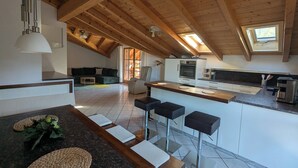 A modern loft-style living space with a kitchen, dining area, and a large skylight. - Apartment Gigi 100 m², 2-6 persons, living room, 3 bedrooms, kitchen, 2x bathroom, WLAN (Unterwössen)