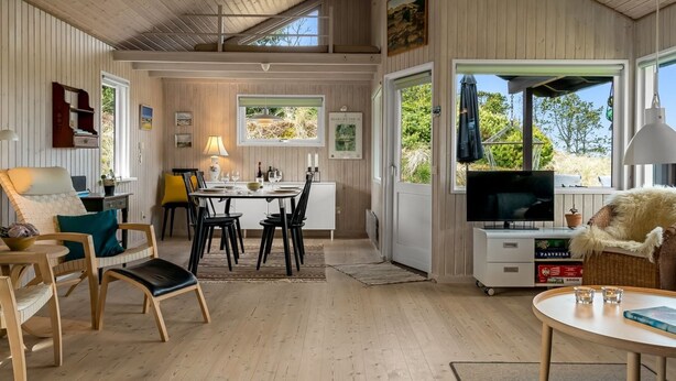 Ett rymligt rum med en matplats, en tv och en mysig sittgrupp med utsikt över omgivningarna.