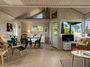 A spacious room with a dining area, a television, and a cozy seating area with a view of the outdoors. - "Thorgny" - 1km from the sea by Interhome (Pandrup)