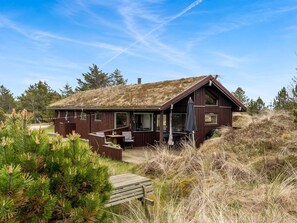 A wooden cabin with a thatched roof, a deck, and a covered outdoor seating area. - "Thorgny" - 1km from the sea by Interhome (Pandrup)