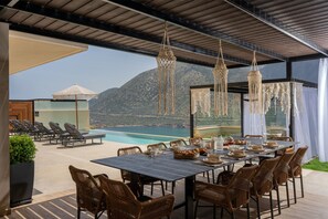 Ein Essbereich mit einem Tisch für sechs Personen, mit Blick auf einen Pool und Berge.