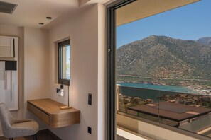 Ein modernes Zimmer mit Schreibtisch aus Holz, einem Stuhl, einem großen Fenster und Blick auf eine Berglandschaft.