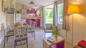 Una cocina moderna con comedor, un espacio de sala con sofá y mesa, y vistas al exterior.