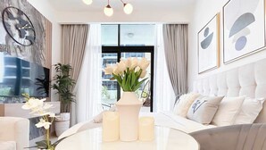 Un salon moderne avec une table basse ronde, un canapé, un téléviseur et une grande fenêtre avec des rideaux.