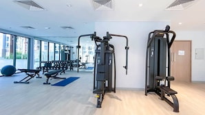 Une salle de sport moderne équipée de matériel d’exercice, dotée de grandes fenêtres et d’un plancher en bois.