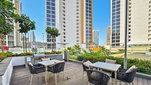 Una terrazza esterna con tavoli e sedie, immersa nel verde e con vista sui grattacieli.