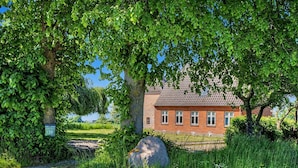 En byggnad med fasad av rött tegel, en trädgård, en stor sten och en skylt med siffror.