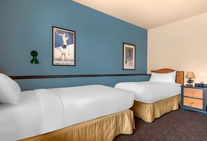 Ein Hotelzimmer mit zwei Einzelbetten, einem Nachttisch mit Lampe und zwei gerahmten Bildern an der Wand.