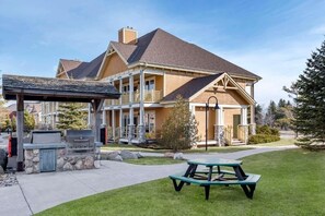 Ein zweistöckiges Haus mit überdachter Terrasse und Grillplatz.