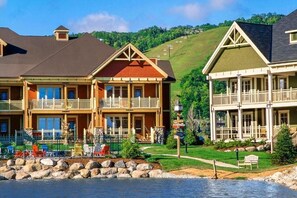 Eine zweistöckige Lodge mit Balkon, Poolbereich und Blick auf einen Hügel.