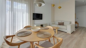A modern living room with a dining table, sofa, and TV. - Sol Marina- Przystań by Grand Apartments (Pruszcz Gdanski)