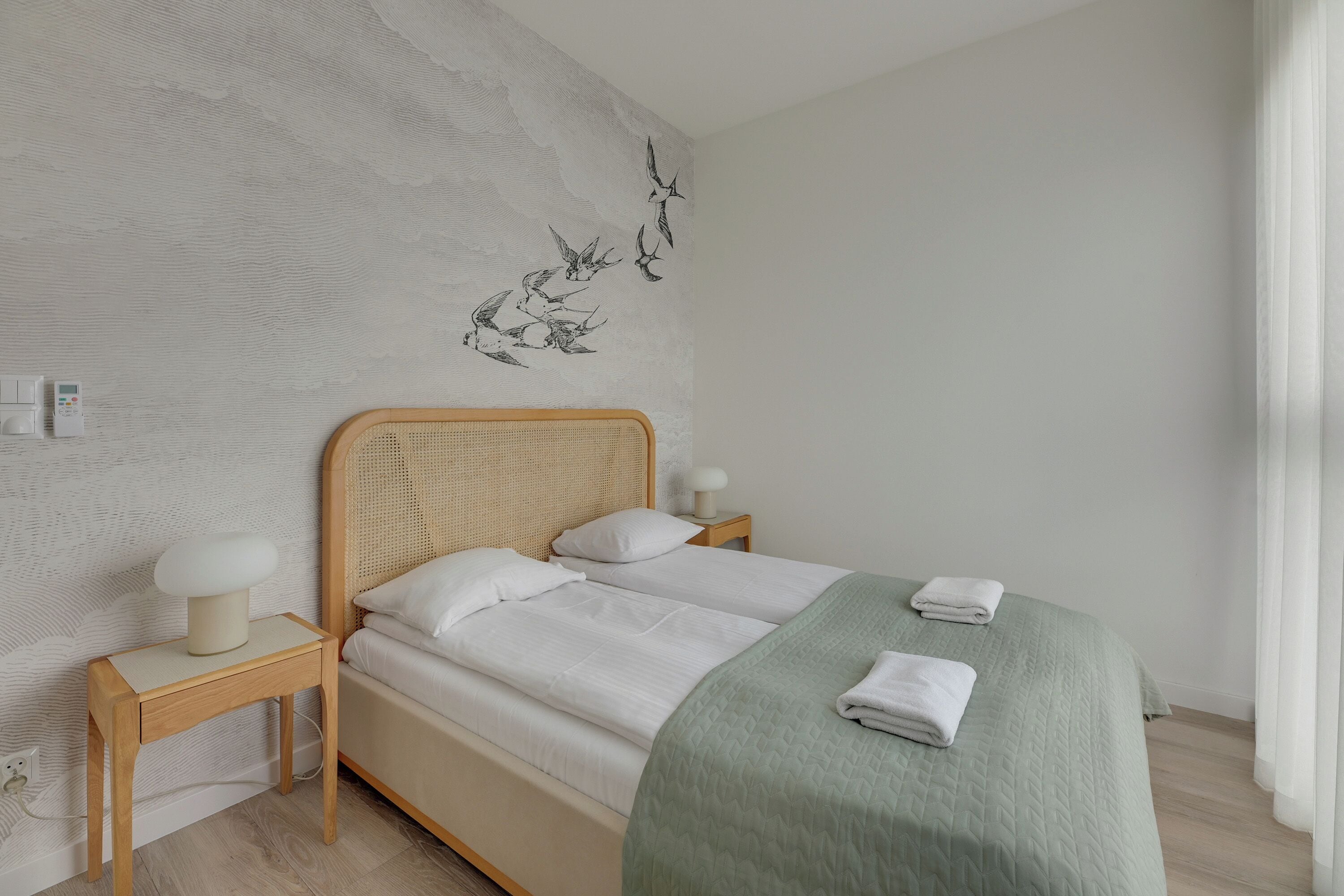 Een slaapkamer met een bed, nachtkastjes, een wandlamp en een kunstwerk aan de muur.
