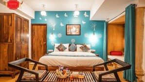 A room with a bed, wooden furniture, a wall with butterfly decals, and a sign above the bed. - Hotel Aurang Heritage (Jaisalmer)