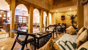 A traditional interior with wooden furniture, arches, and a sign reading 'PRAMANA EXP.' - Hotel Aurang Heritage (Jaisalmer)