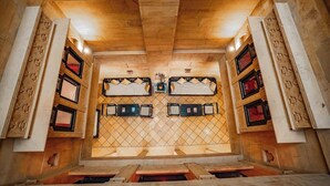 A room with a wooden ceiling, a patterned wall, and a central window. - Hotel Aurang Heritage (Jaisalmer)